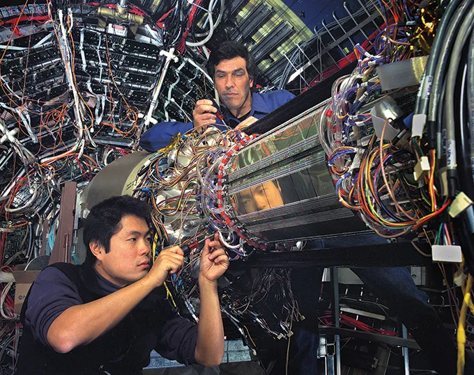 032026_colliders_inline2 A photo of two scientists working on part of the STAR detector